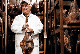 Sam Edwards holding a ham in the curing house