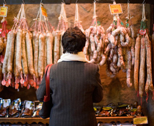 woman looking at hanging chorizos in the market